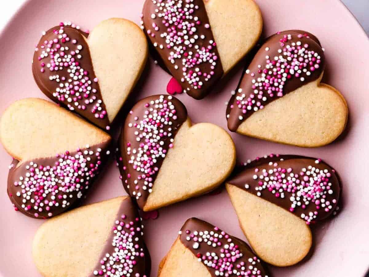 Valentine's day cookies on a pink plate with sprinkles.
