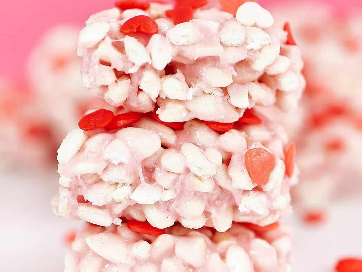 A stack of valentine's day krispy treats on a pink background.