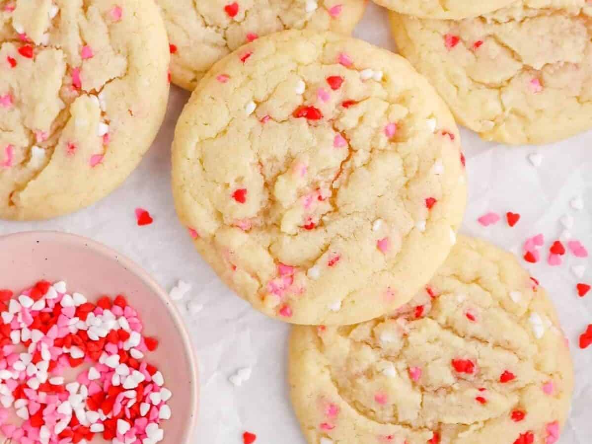 Valentine's day cookies on a white plate with sprinkles.