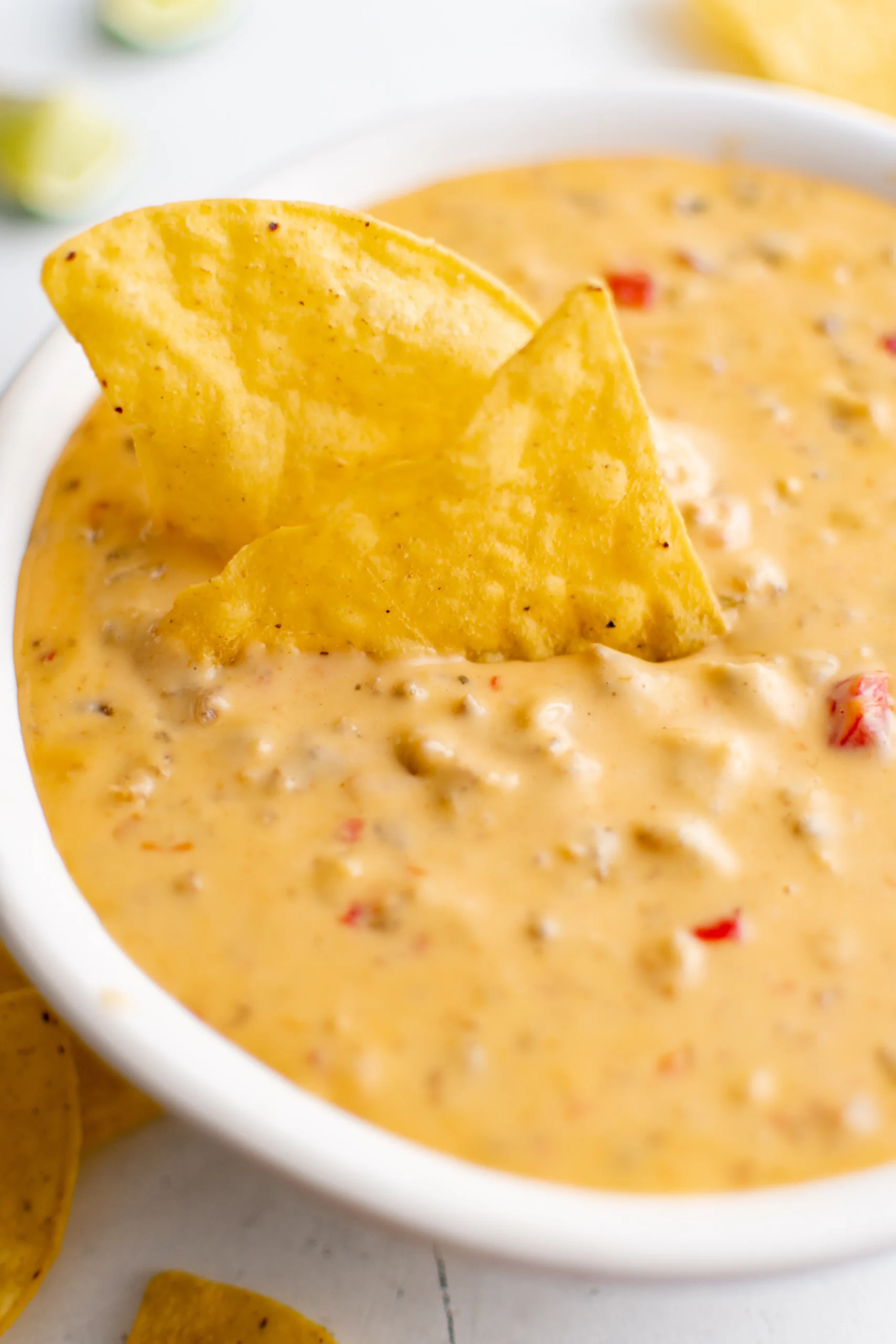 A delicious bowl of ground sausage dip with a chip in it.
