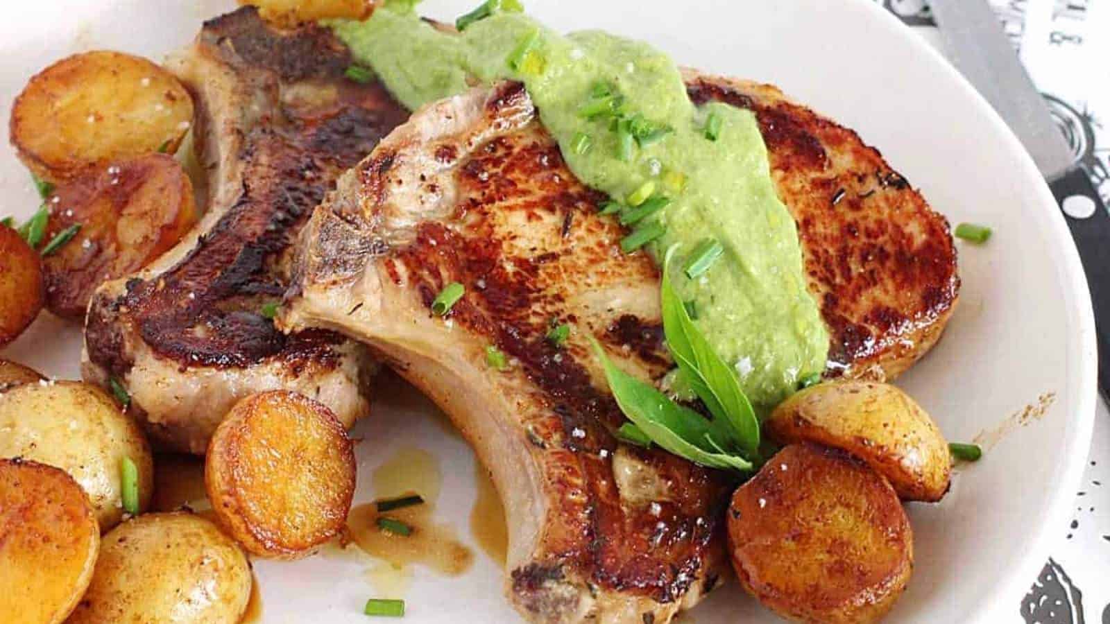 A plate with pork chops, potatoes and guacamole.