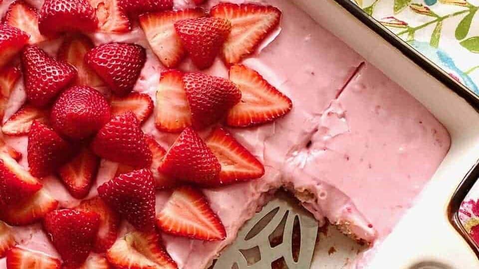 Strawberry cheesecake in a baking dish with strawberries on top.