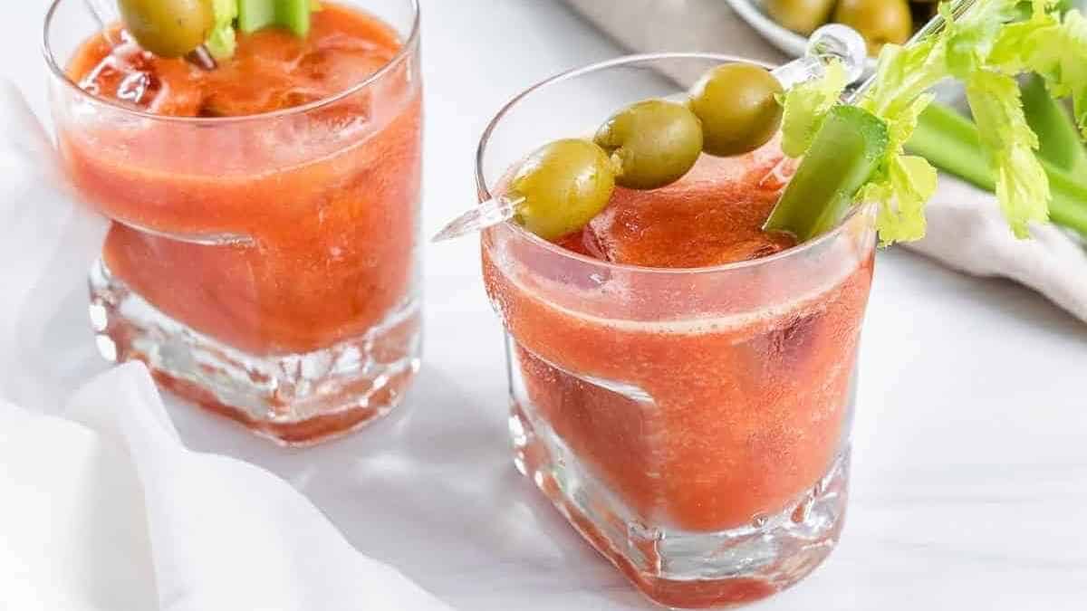 Two glasses of bloody mary with olives and olives.