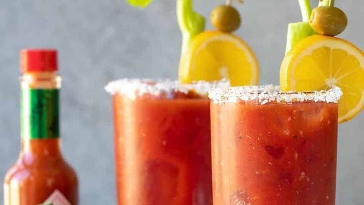 Two glasses of bloody mary with garnishes.