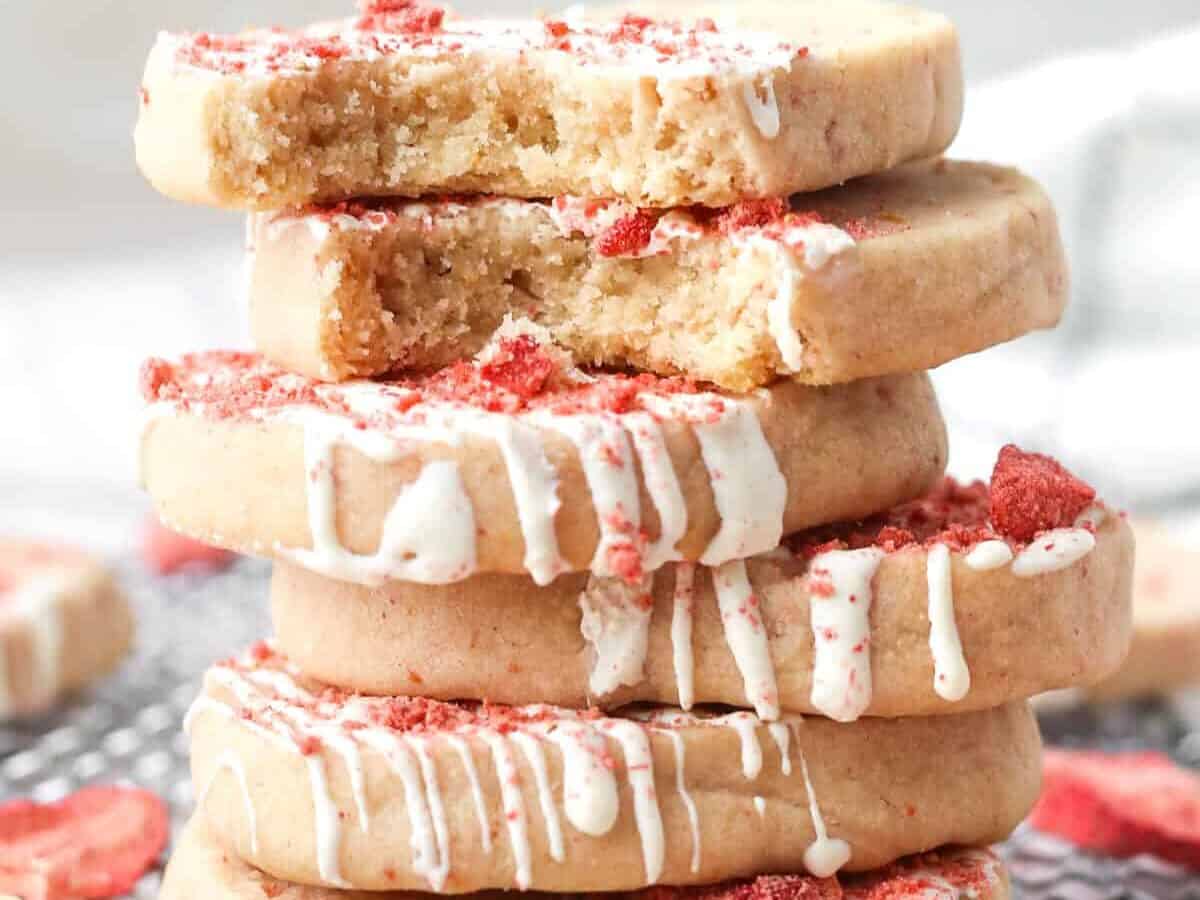 A stack of cookies with white icing and red sprinkles.