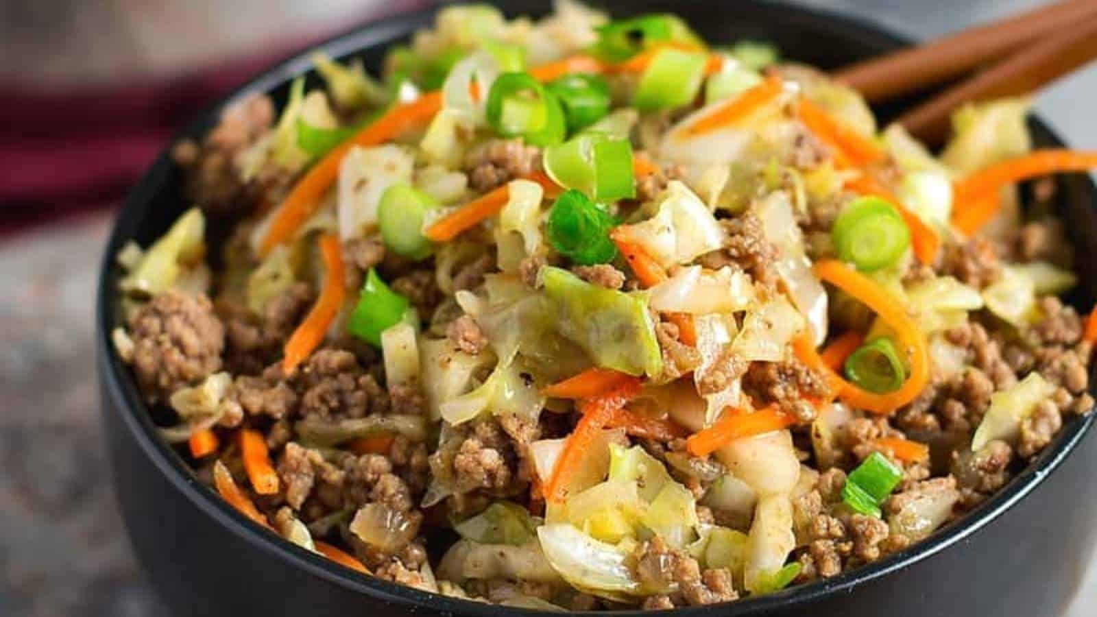 A bowl of meat and cabbage in a bowl with chopsticks.