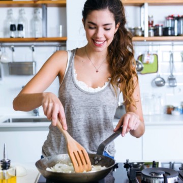 A woman is preparing food in a frying pan.