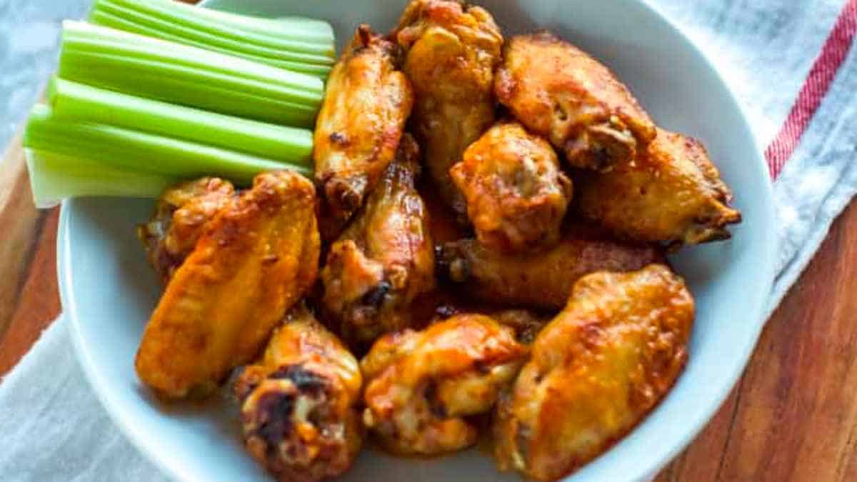 Chicken wings on a plate with celery and celery sticks.