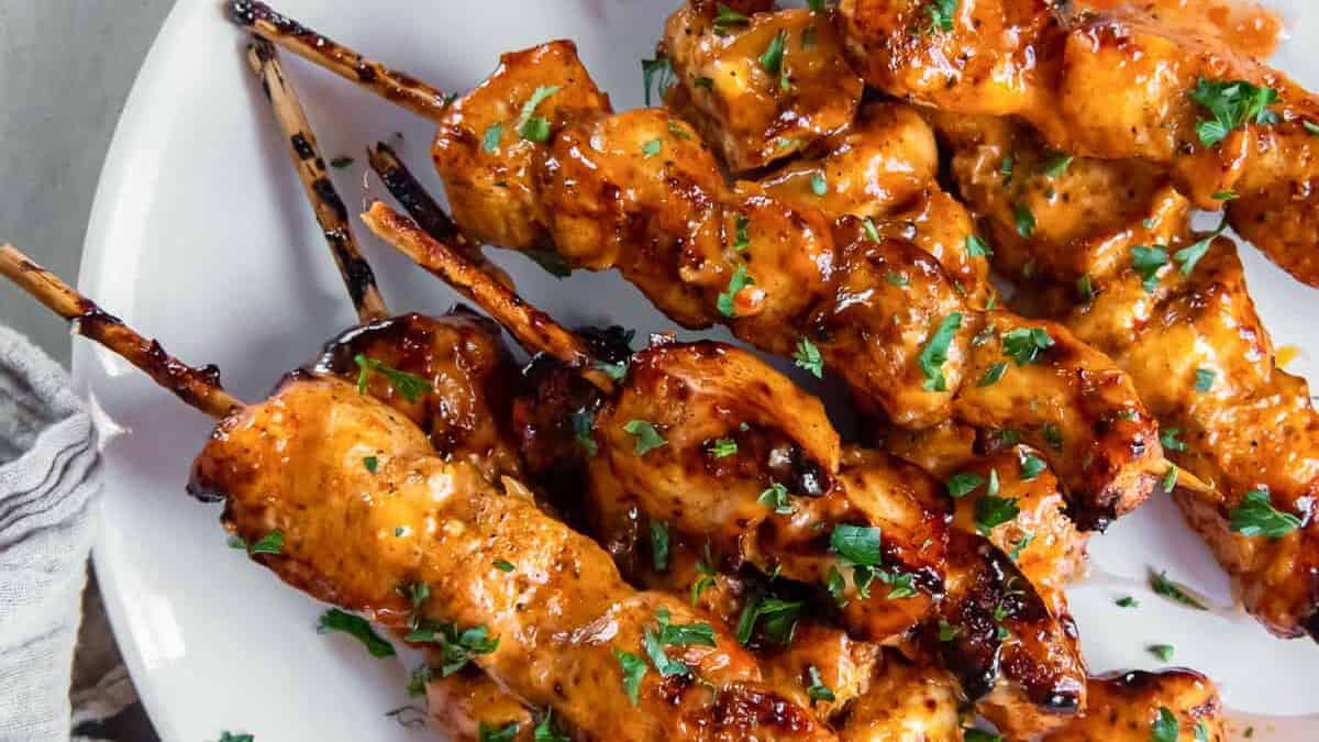 Chicken skewers on a plate with sauce.