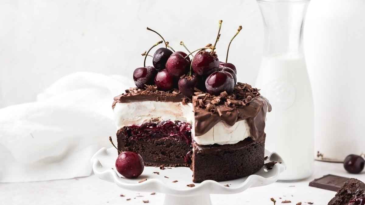 A chocolate cake with cherries on a white plate.