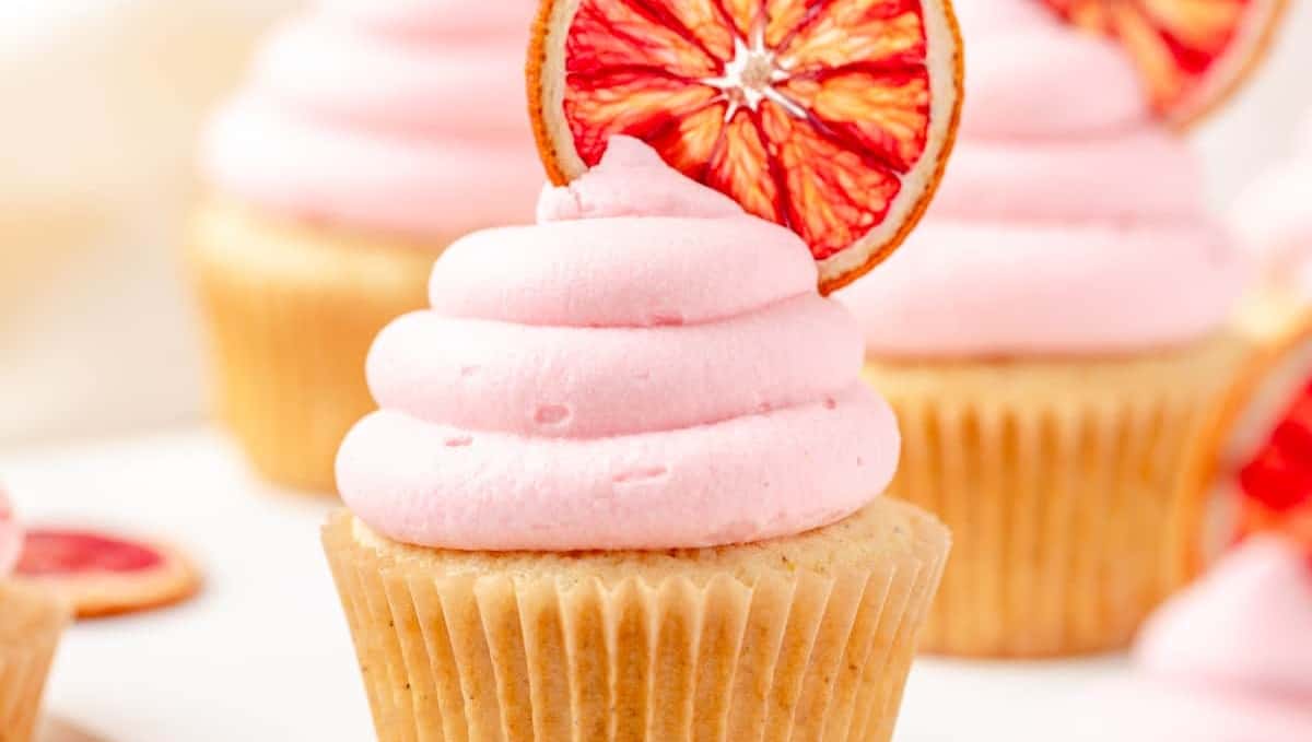 Blood orange cupcakes with pink icing on a white plate.