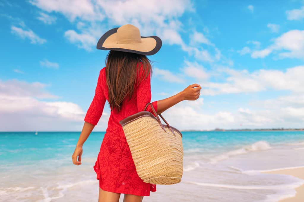 A woman in a red dress walking on the beach.