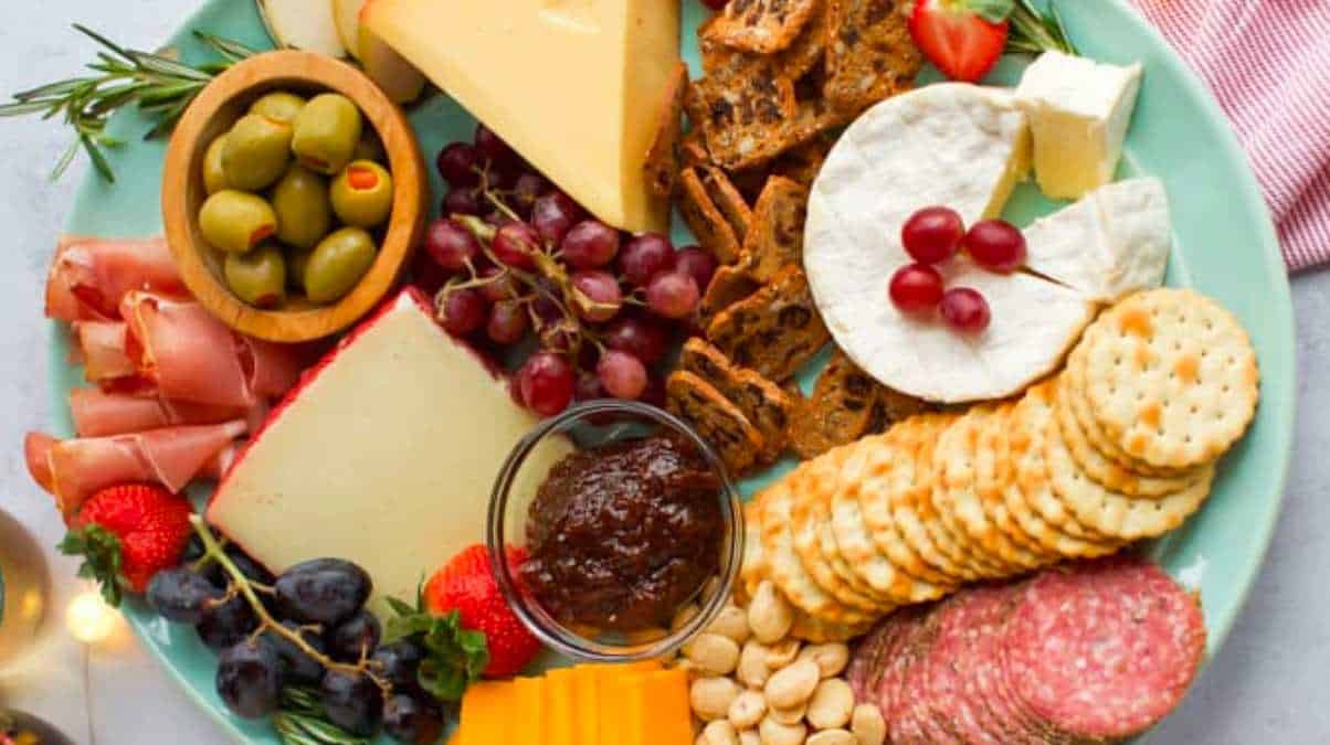 A plate with cheese, crackers, grapes and nuts.