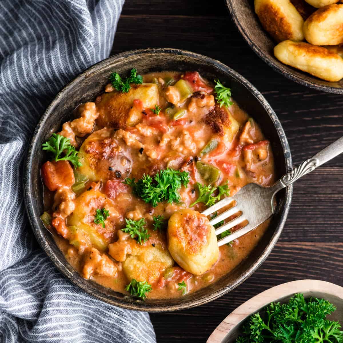A delicious bowl of sausage stew with potatoes, topped with fresh parsley.