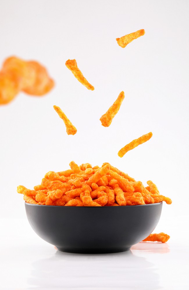 Cheesy chips in a bowl on a white background.