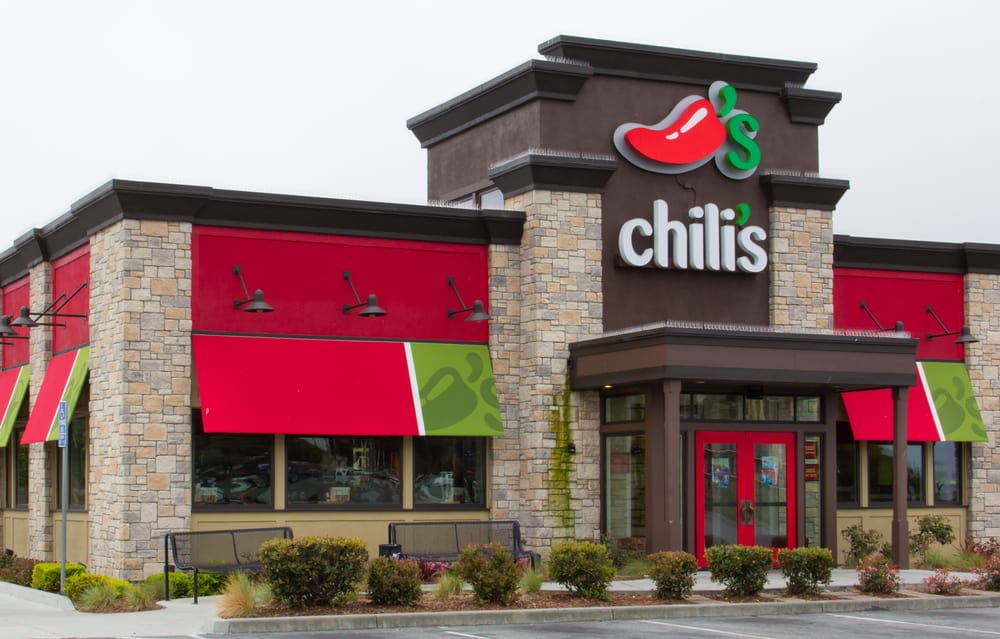 A chili's restaurant with red and green awnings that offers a gluten-free menu.