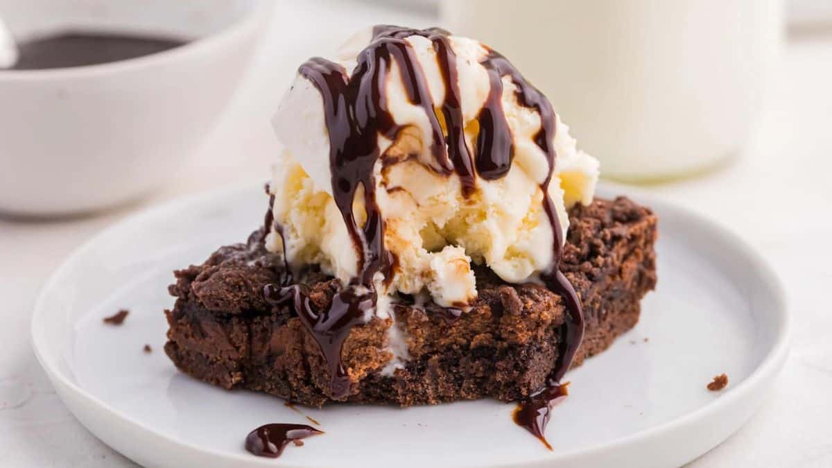 A plate of chocolate brownie with ice cream and whipped cream.