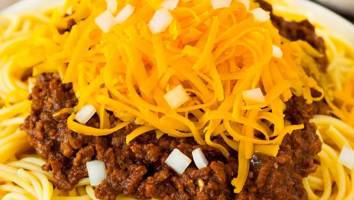 A plate of spaghetti with chili and cheese on it.