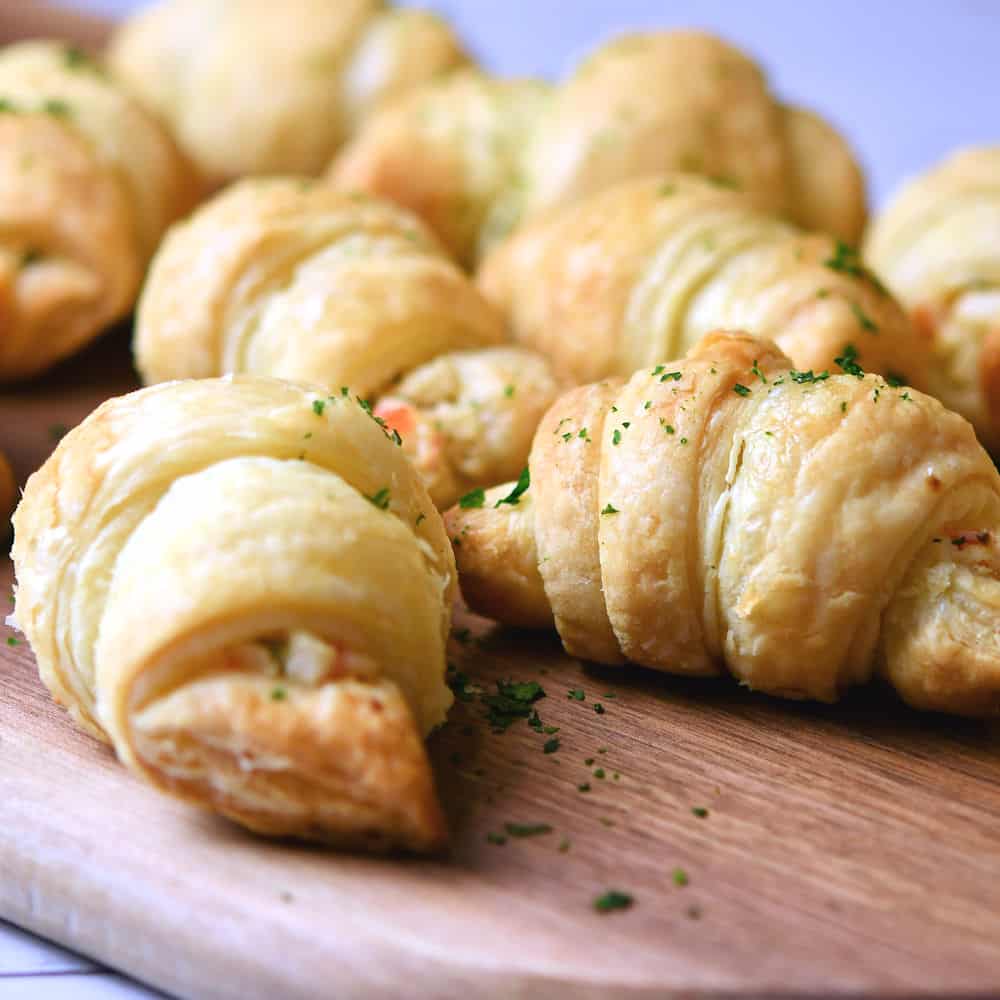 A tray of croissants on a wooden cutting board, perfect for enjoying alongside your favorite imitation crab recipes.