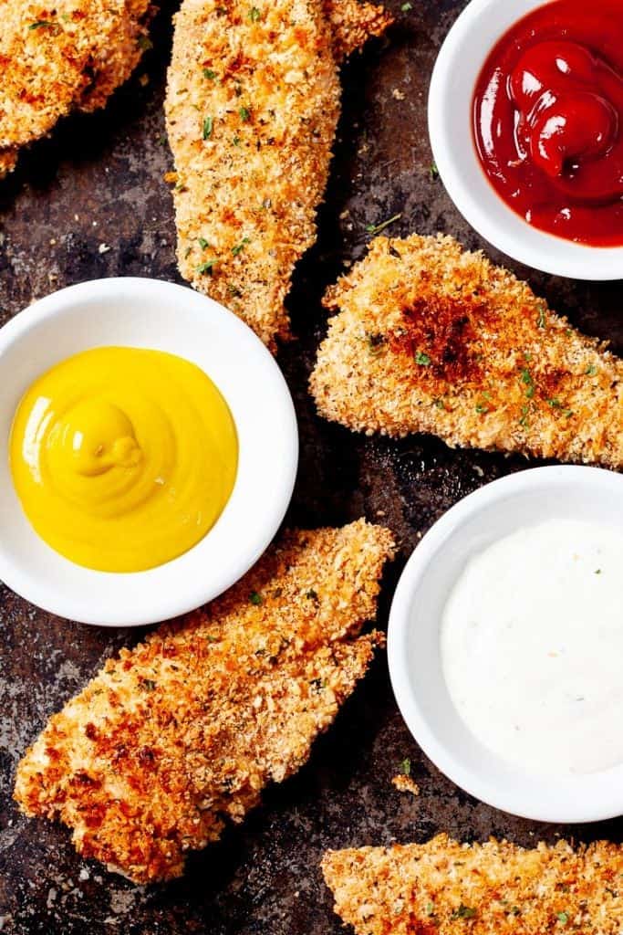 Delicious chicken tenders with a delectable dipping sauce, served on a plate.