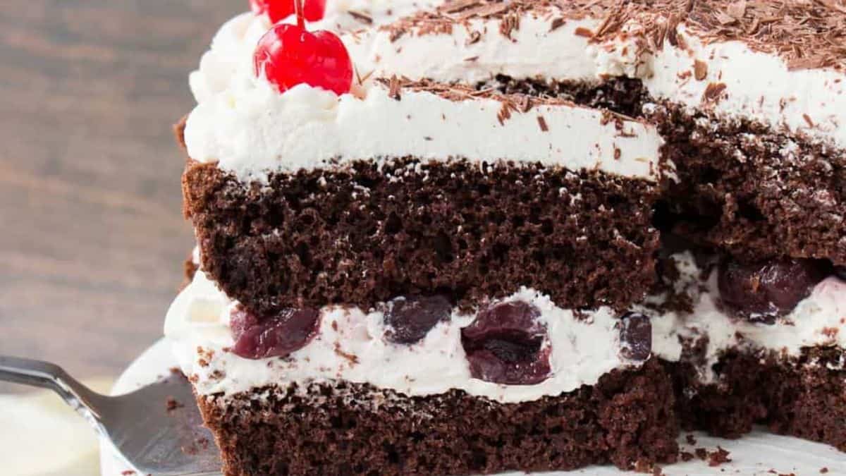 A slice of chocolate cake with cherries on top.