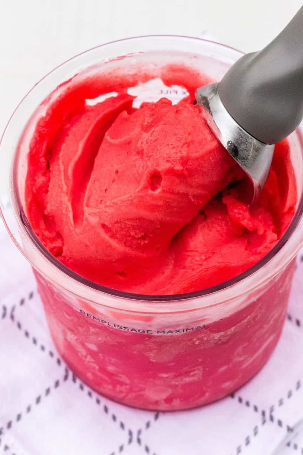 Cherry pie sorbet in a bowl with a spatula.