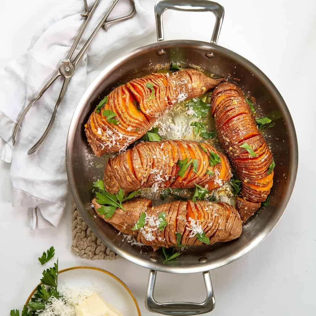 Sweet potatoes in a pan with parmesan cheese and parsley.