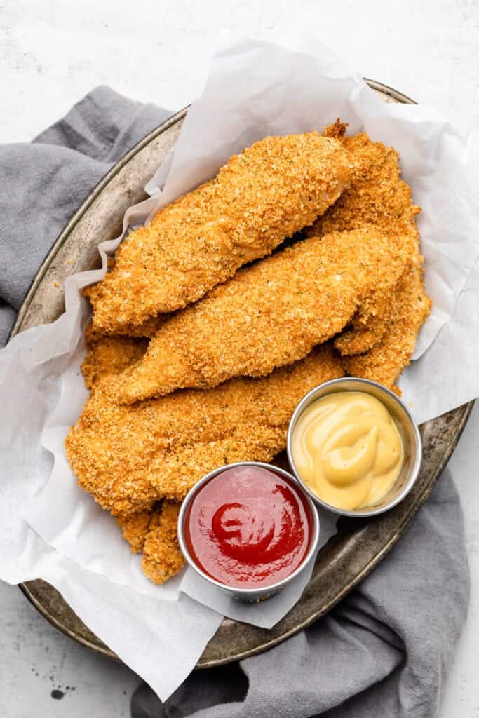 Delicious fried chicken tender recipes with ketchup and dipping sauce on a plate.
