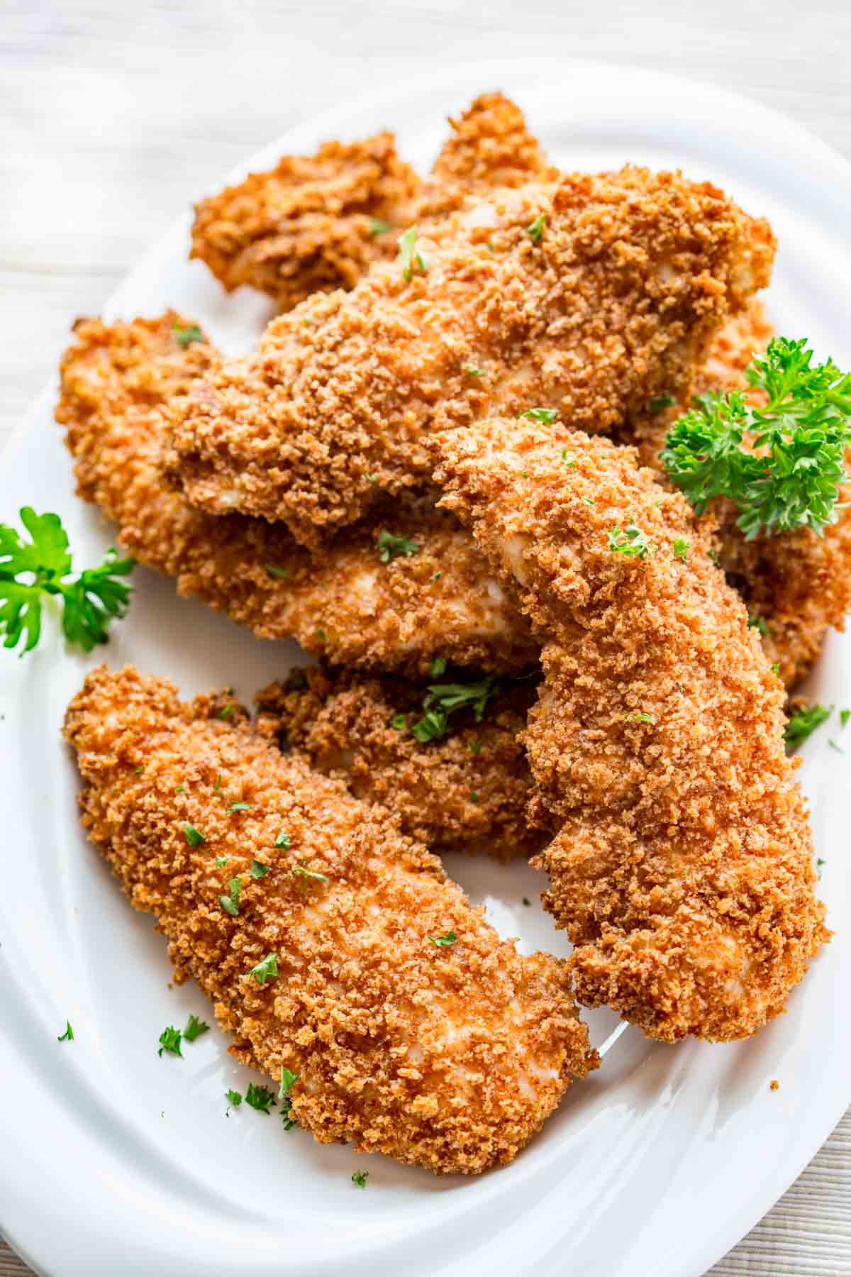 Chicken tenders on a white plate with parsley.