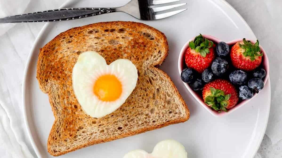 A plate of toast with a heart shaped egg and berries.