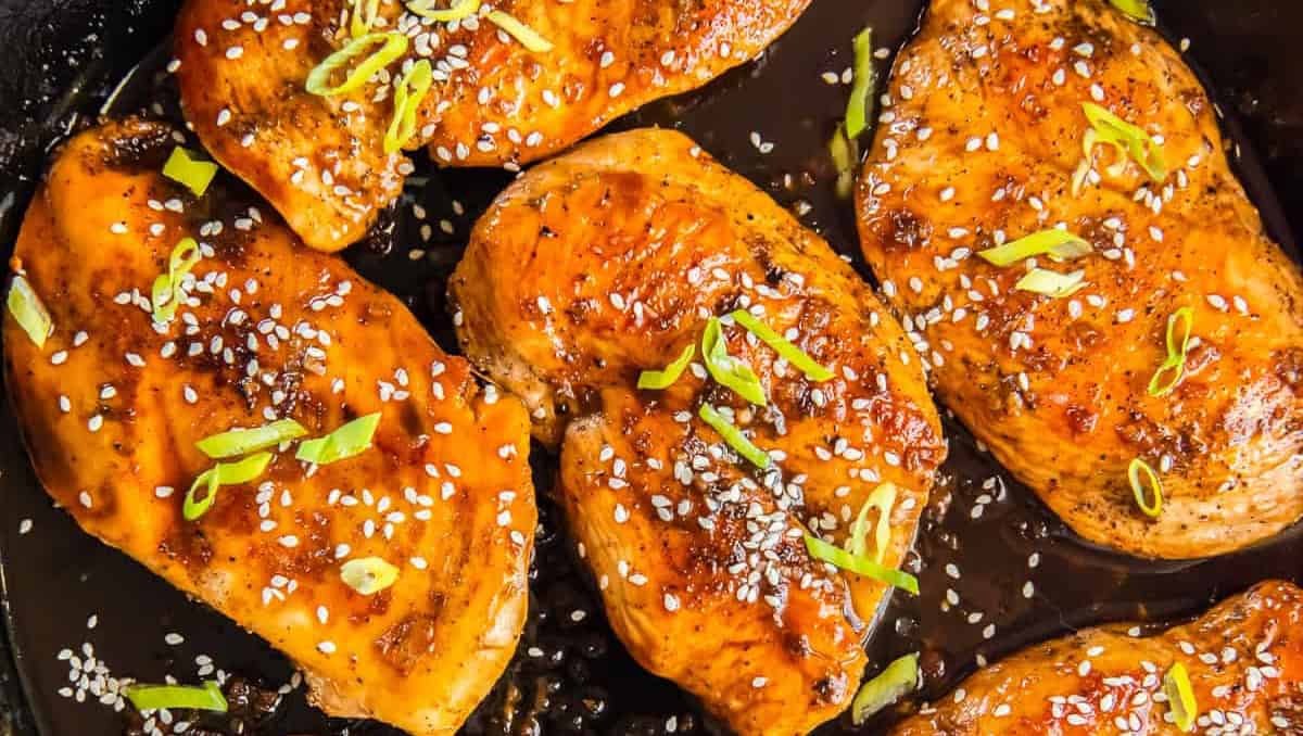 Sesame chicken in a skillet with rice and sesame seeds.