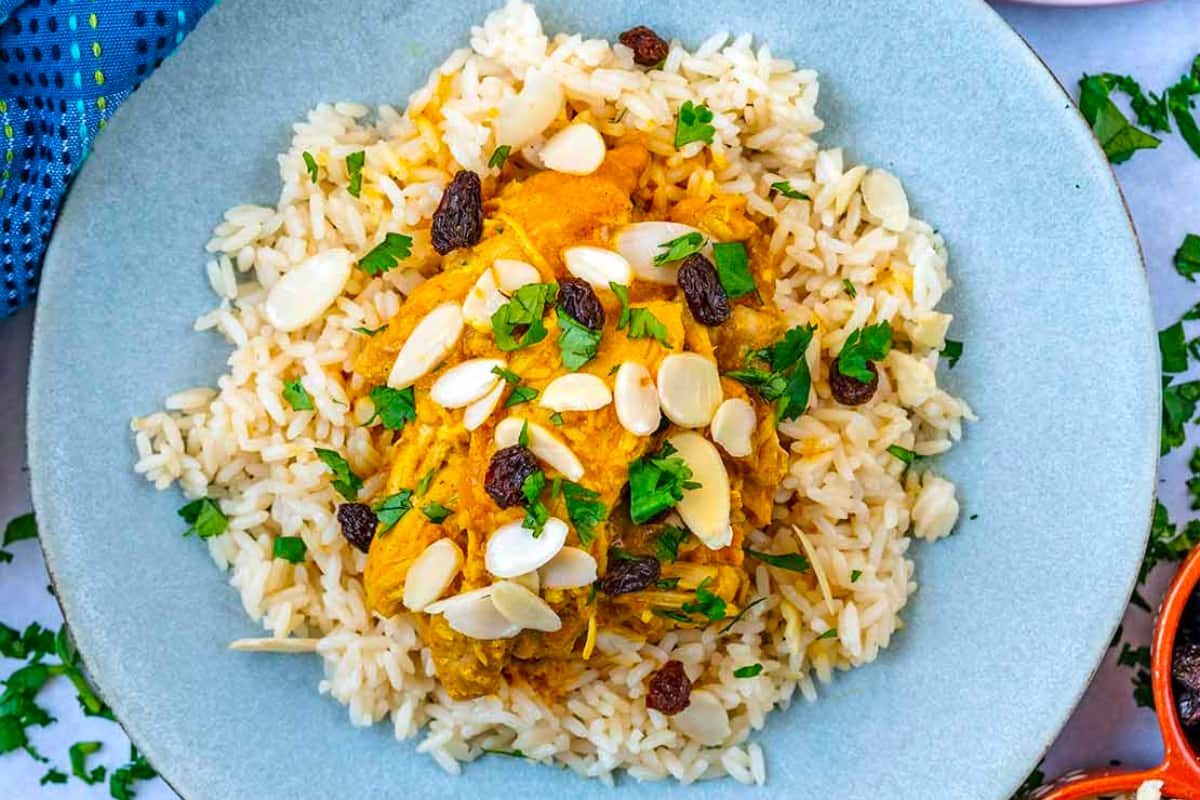 A plate of rice and chicken with raisins and almonds.