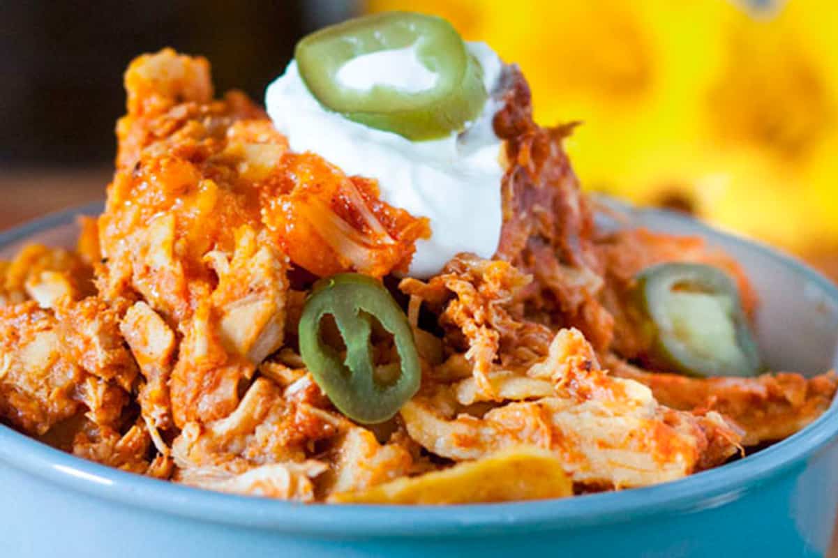 Mexican chicken nachos in a bowl with sour cream and jalapenos.