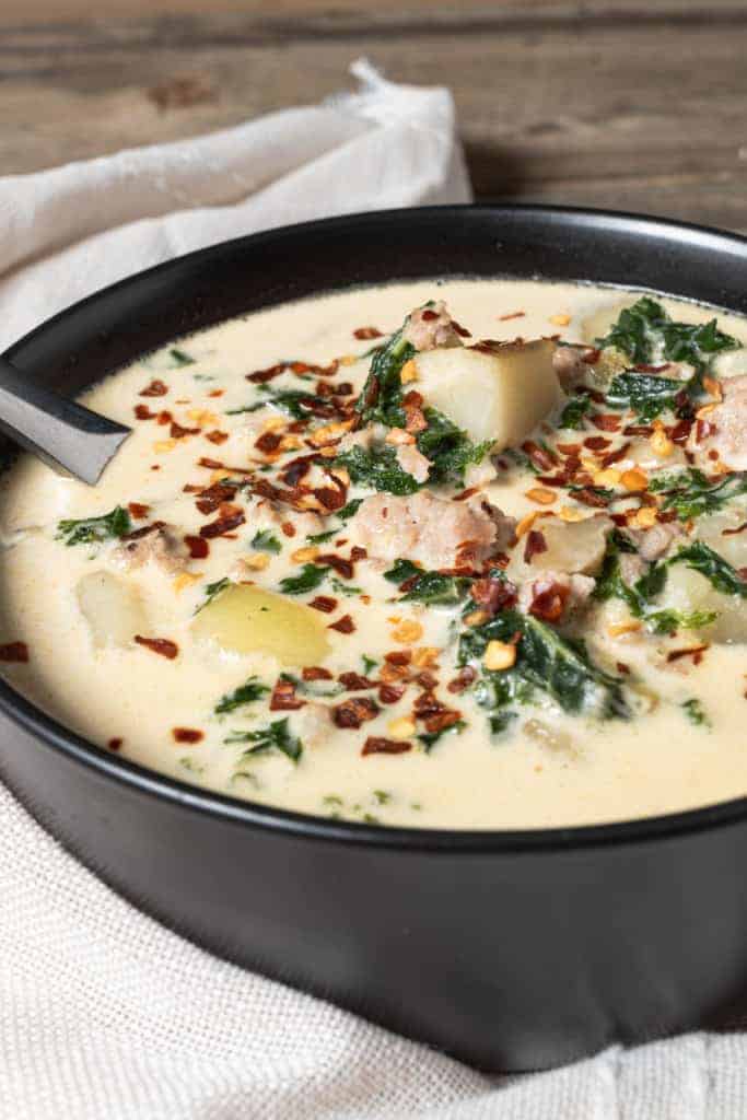 A bowl of soup with spinach and potatoes.