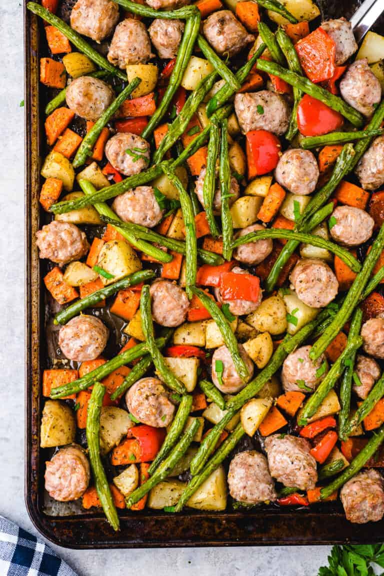A baking sheet filled with sausage and vegetables.