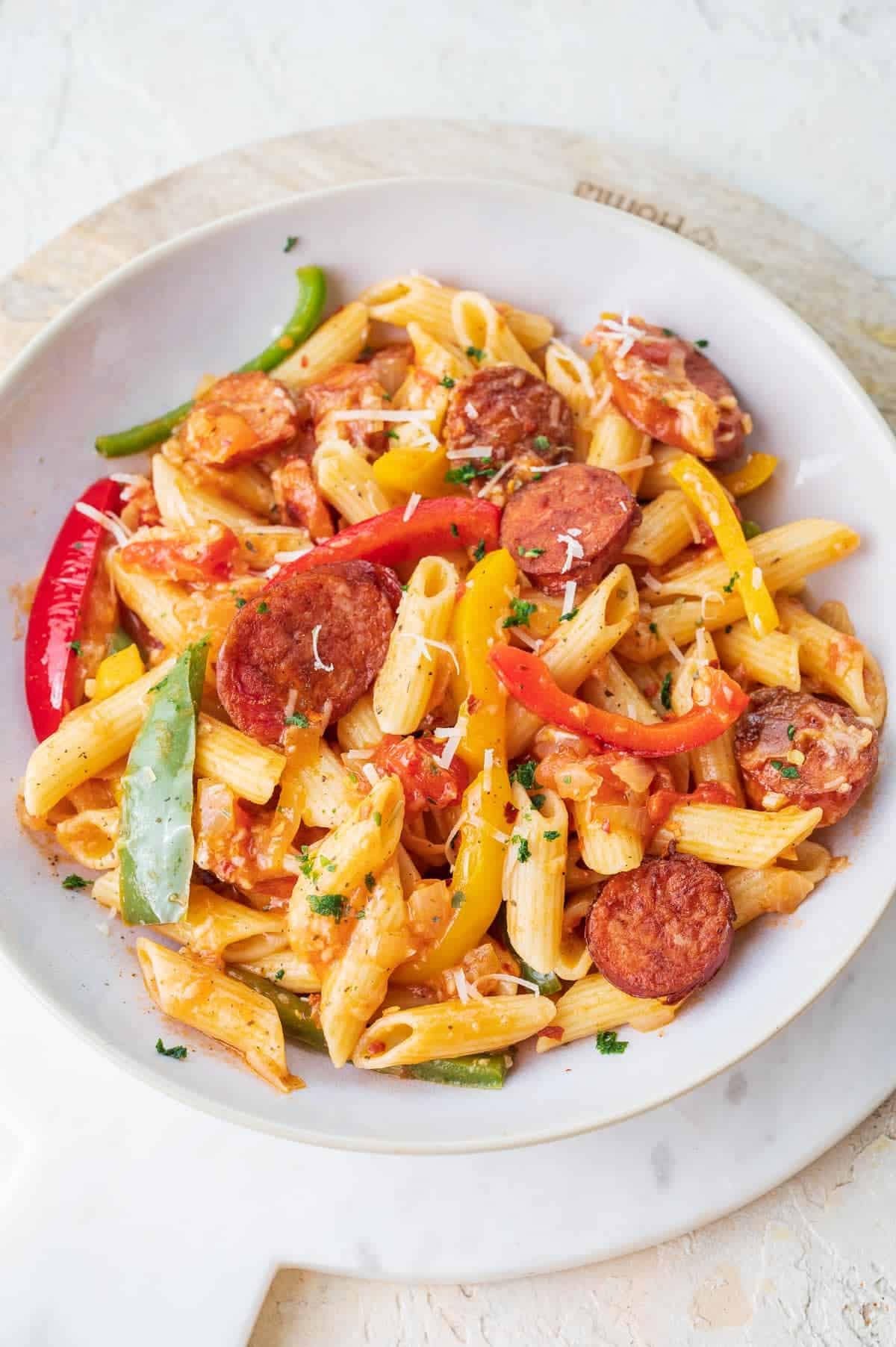 Delicious penne pasta dish featuring sausage and peppers served on a white plate.