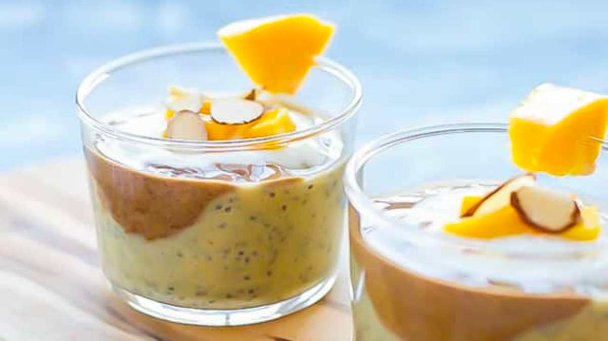 Two glasses of mango pudding on a wooden cutting board.