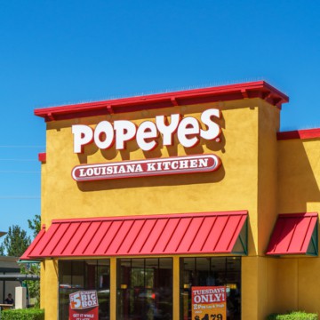 A yellow building with a red roof that also offers a Popeyes gluten-free menu.