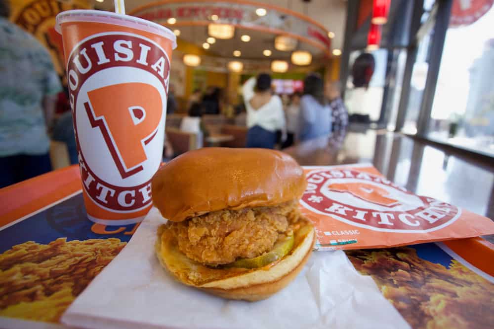     A gluten-free chicken sandwich sits on a tray next to a drink at Popeyes.