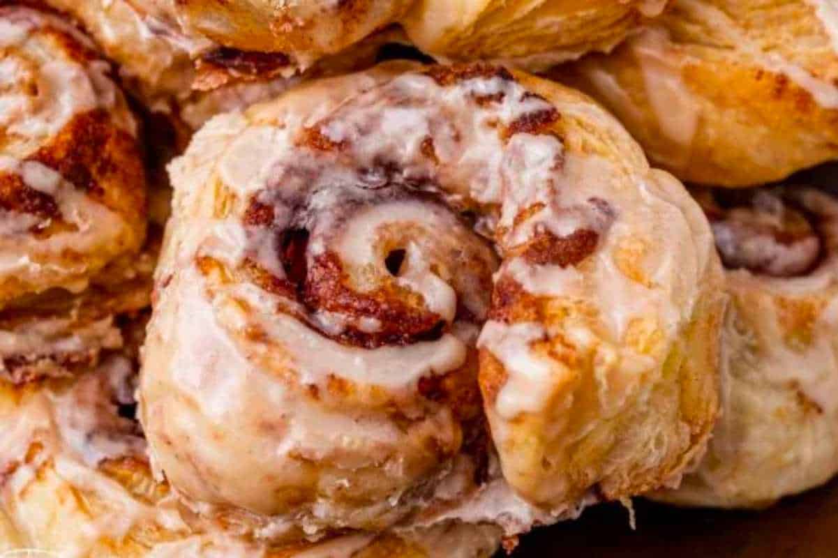 A pile of cinnamon rolls with icing on top.