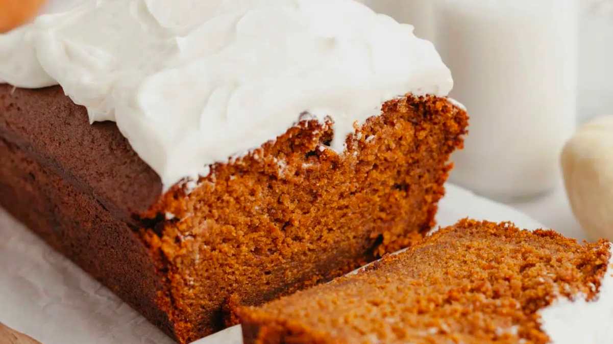 A slice of pumpkin bread with whipped cream on top.