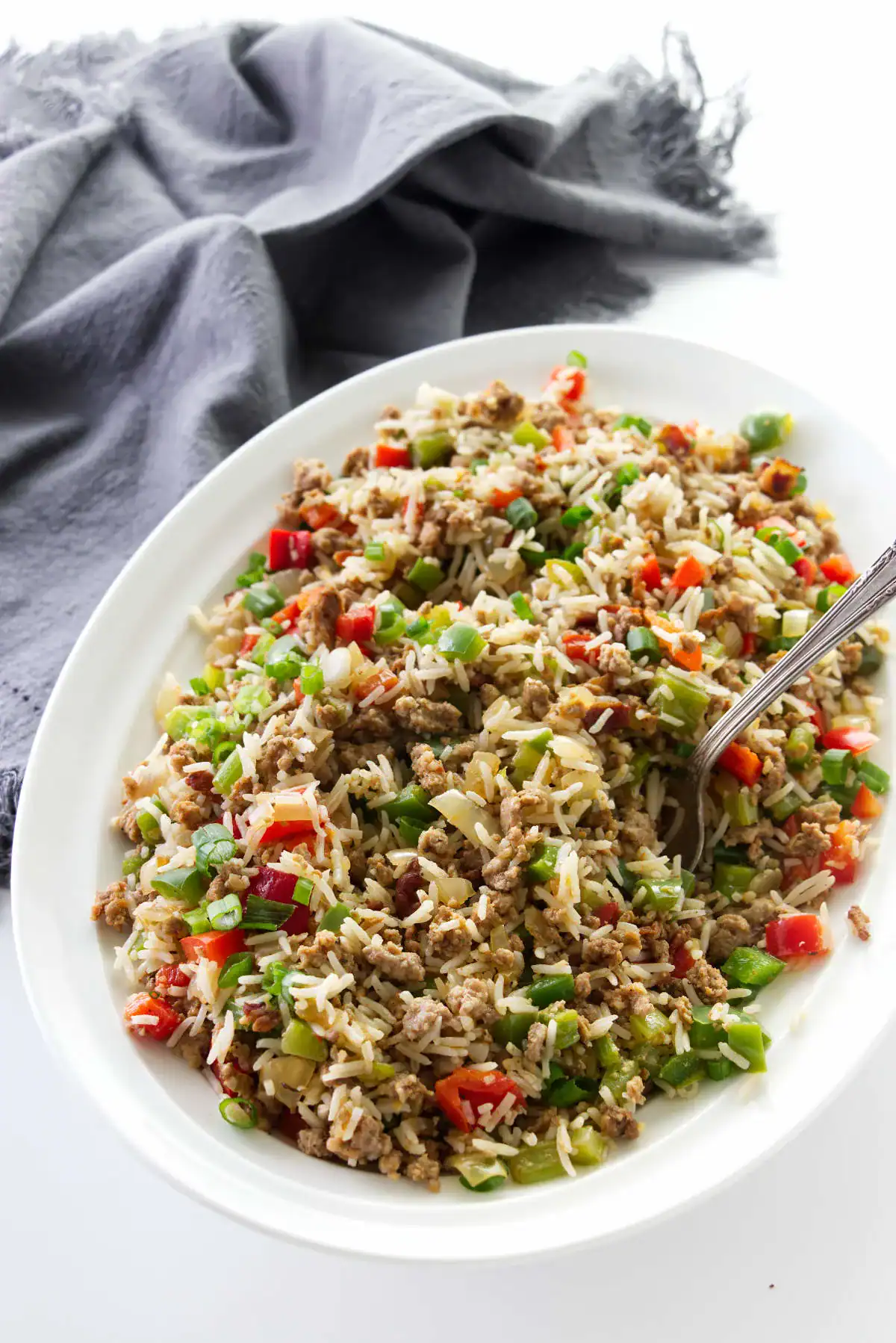 A plate with rice and vegetables topped with ground sausage.