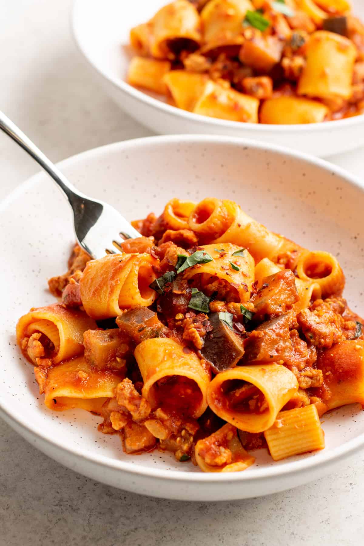 A plate of pasta with a fork and ground sausage recipes.