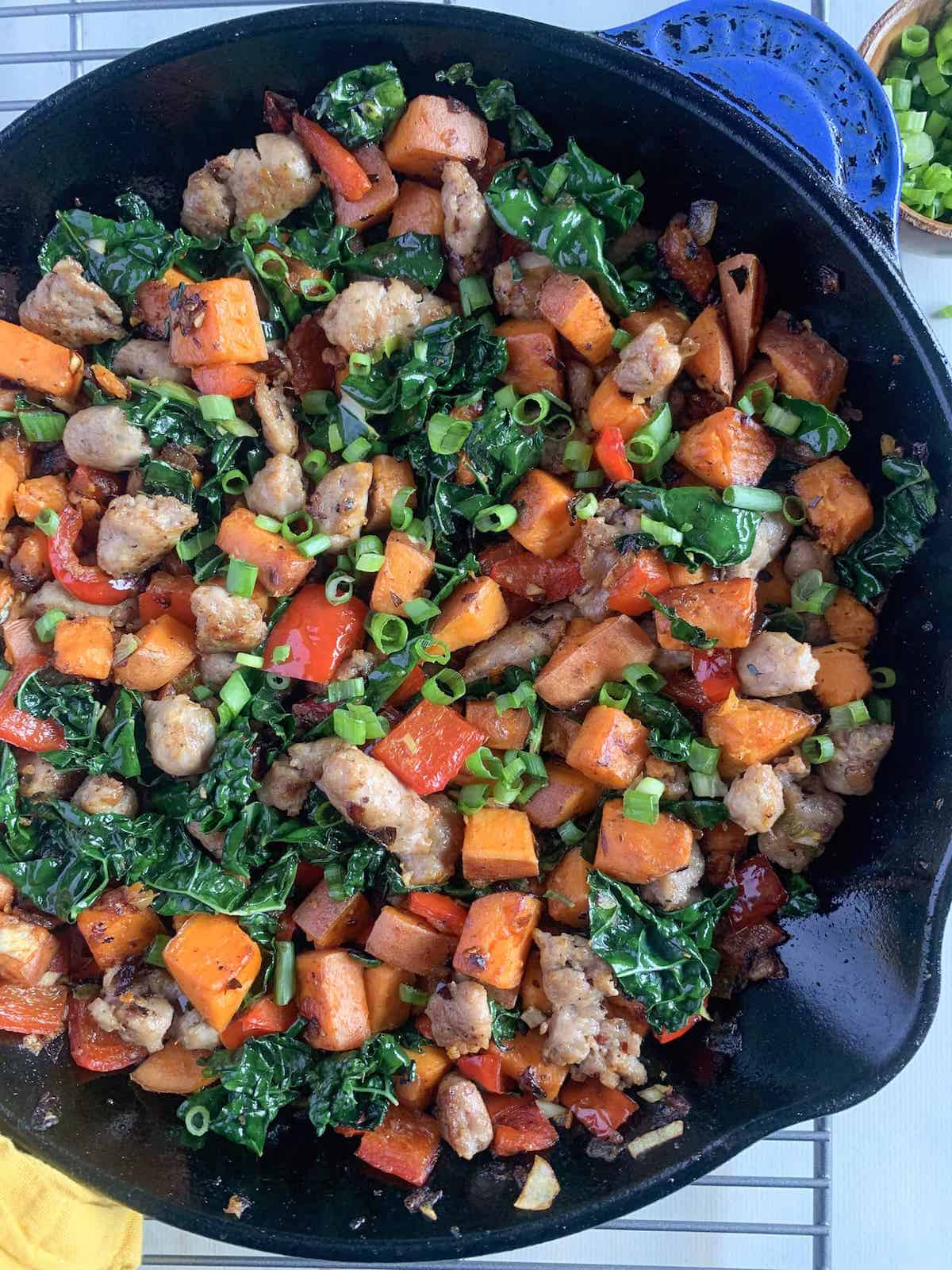 A skillet full of chicken, sweet potatoes and kale with a touch of ground sausage for added flavor.