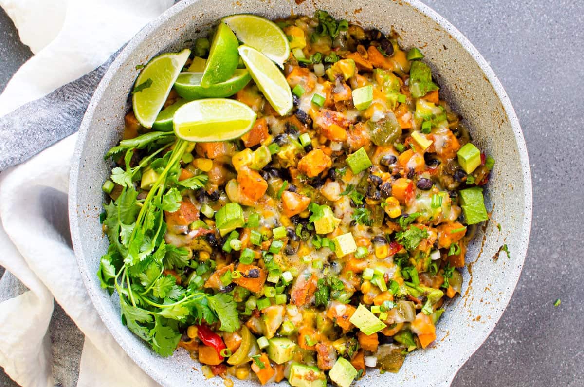 A skillet filled with vegetables and a lime wedge.