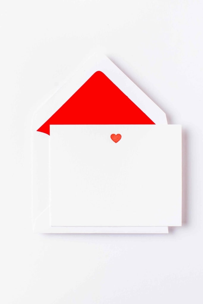 A white envelope with a red heart on it.