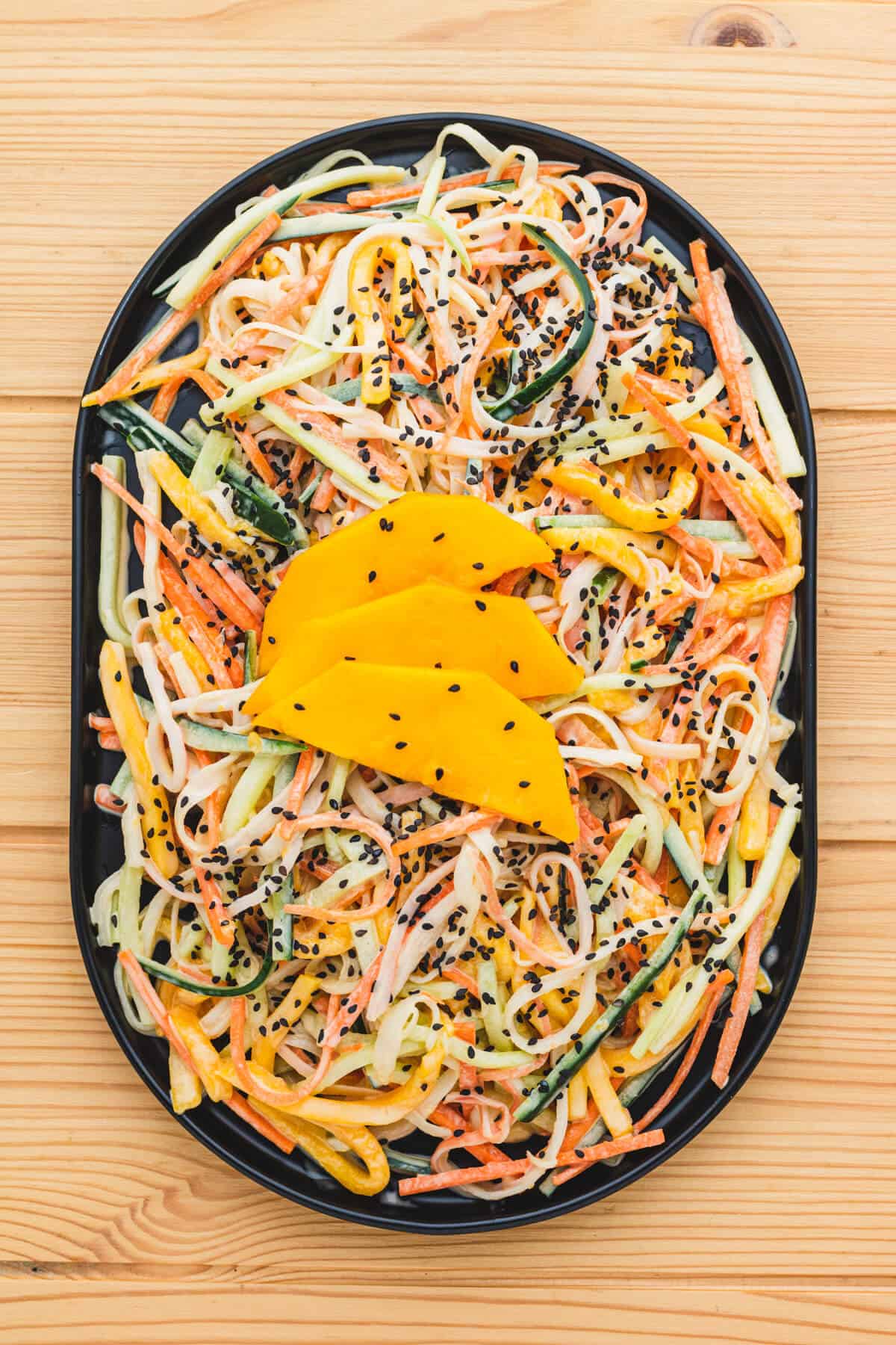 A plate topped with an imitation crab salad of carrots, cucumbers, mangoes and sesame seeds.
