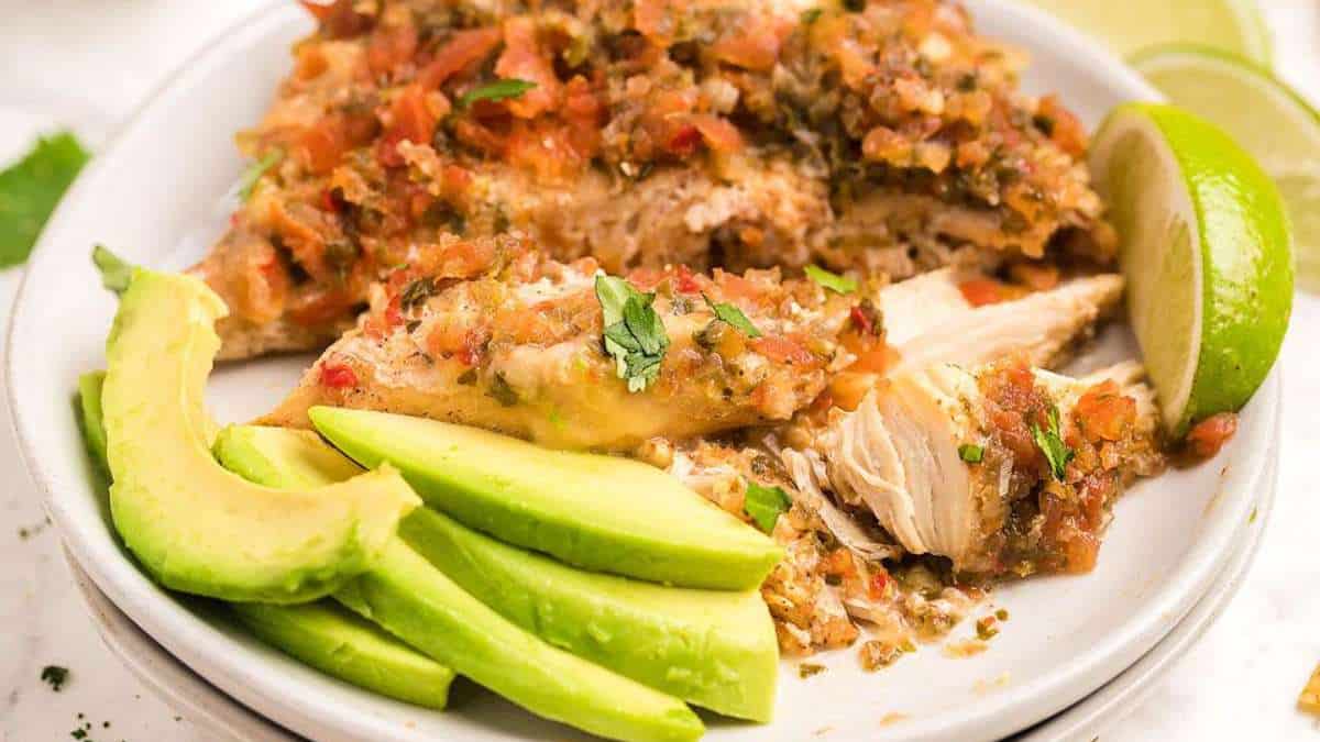 A white plate with chicken and avocado on it.