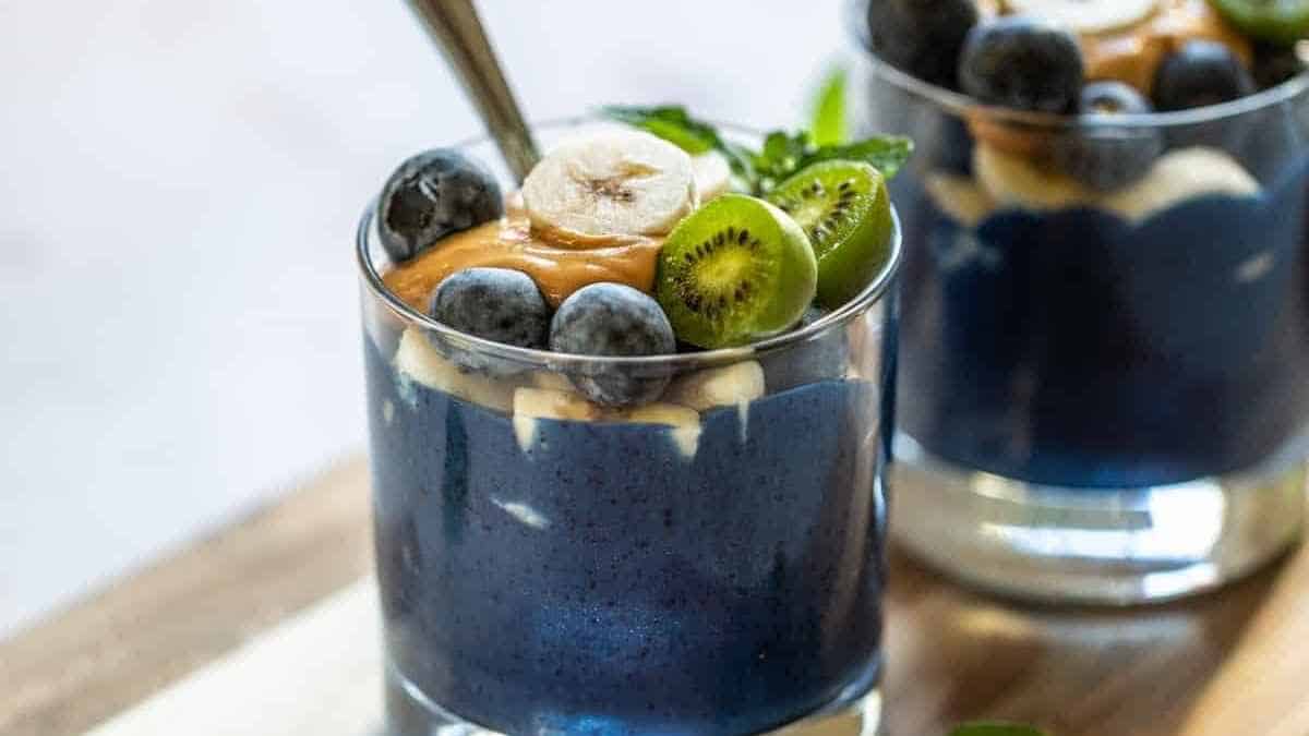 Two glasses of blueberry pudding with banana and kiwi.