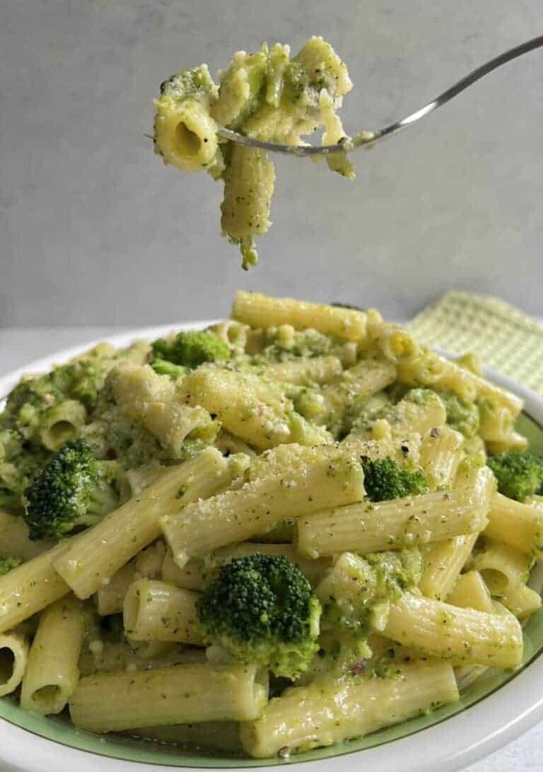 Forkful of pasta with broccoli over bowl.